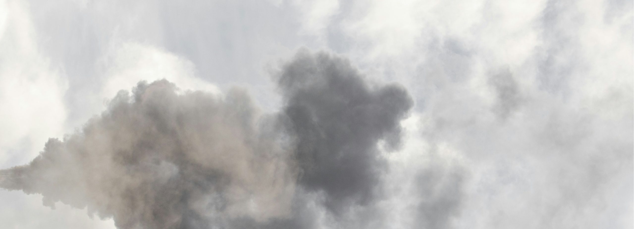 A photo of grey exhaust clouds contrasting with natural clouds.